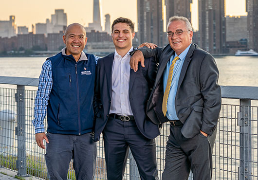 Vice President Roni Barami (center) and President Vebi Barami (right) tip their hats to Darwin Lee (left) of The Blue Book Network for his referrals to potential clients.